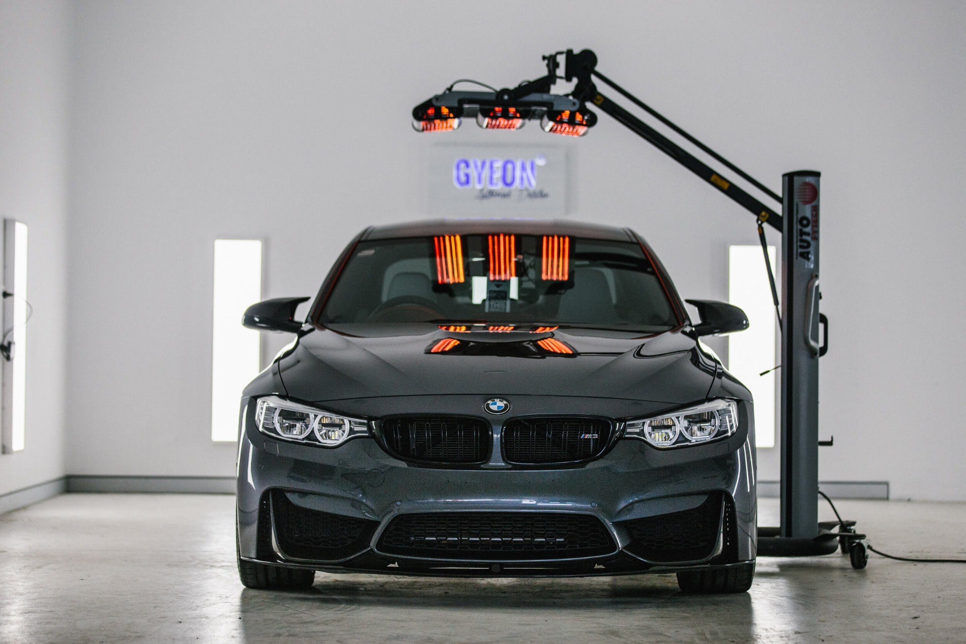 A dark grey BMW M3 under inspection lighting in the Midwest Auto Pros bay